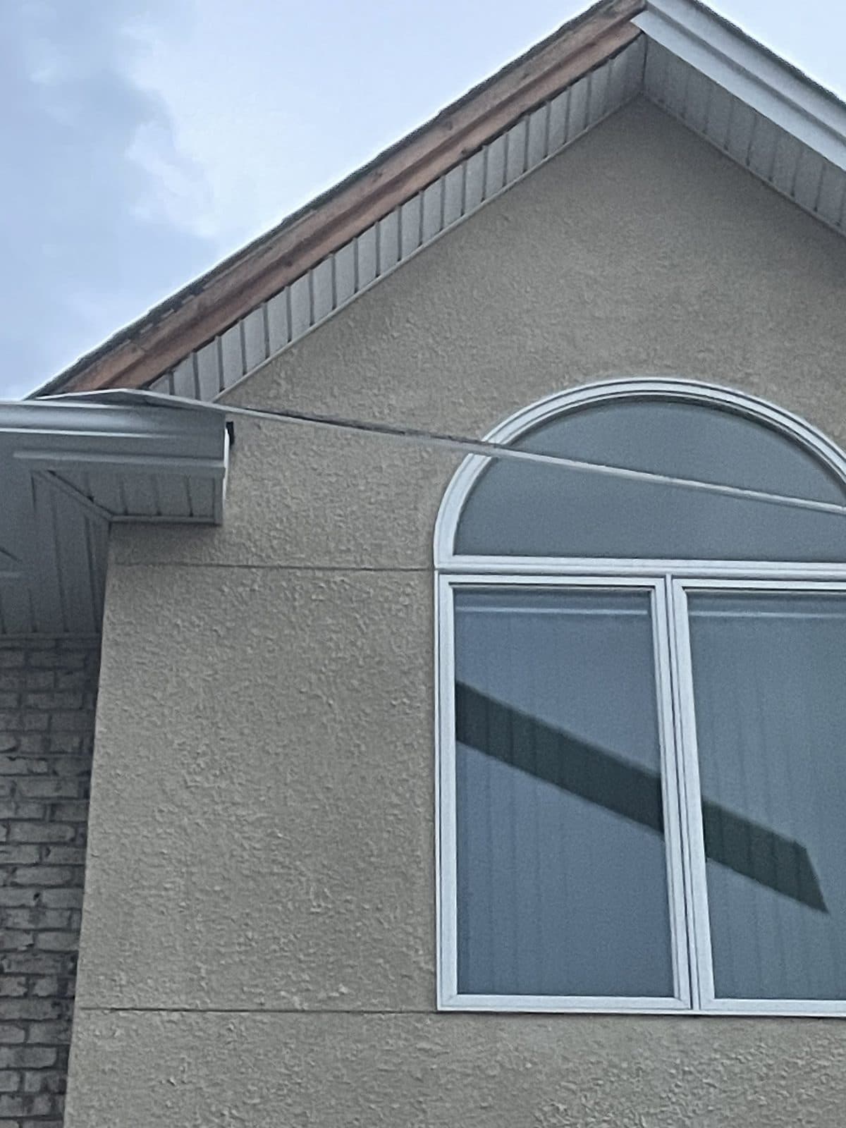 White half-round arched Palladian window over two rectangular units in the stucco gable of a Fair Lawn, NJ home, installed by Precision Windows & Roofing