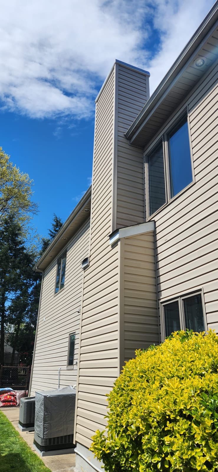 Chimney chase clad in vinyl siding matched to the wall it runs up, with a new metal chase cover on top, on a two-storey New Jersey home