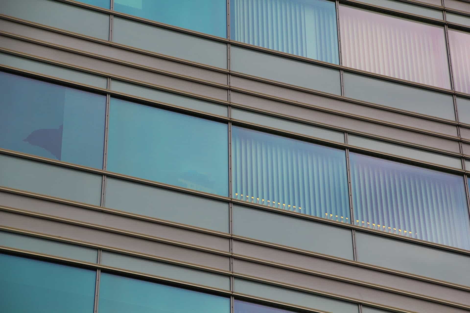 Rows of blue-green tinted windows between horizontal metal bands on a commercial building